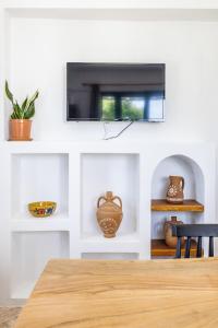 a living room with a tv on a white wall at Anatoli Peak Cottage in Skopelos Town