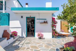 a white house with a blue door and flowers at Anatoli Peak Cottage in Skopelos Town