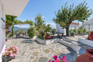 a patio with a table and chairs and flowers at Anatoli Peak Cottage in Skopelos Town