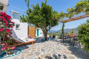a patio with a table and chairs and flowers at Anatoli Peak Cottage in Skopelos Town +24 photos