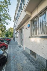 a sidewalk next to a building with parked cars at Cozy Downtown Rooms in Warsaw