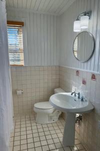a bathroom with a sink and a toilet and a mirror at 04-The Seashell Suite at The Castle Inn in Ocracoke