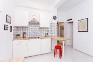 a kitchen with white cabinets and a red stool at Cozy Downtown Rooms in Warsaw