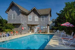 a house with a swimming pool with chairs and an umbrella at 04-The Seashell Suite at The Castle Inn in Ocracoke +3 photos