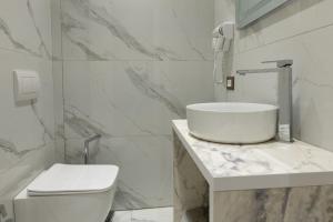 a white bathroom with a sink and a toilet at Sea La Vie Hotel in Durrës