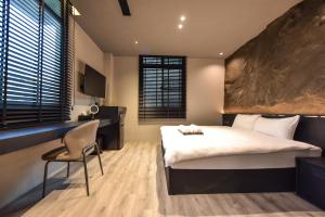 a bedroom with a bed and a desk and a chair at 貳宿文旅 in Tainan