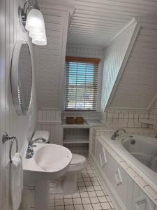 a white bathroom with a sink and a tub at 06-Harbor Suite at The Castle Inn in Ocracoke