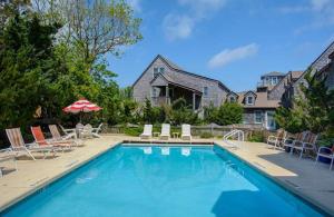 a swimming pool with chairs and umbrellas in front of a house at 08-Flight Suite at The Castle Inn in Ocracoke