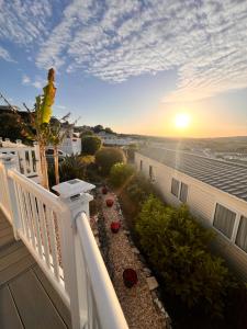 a balcony with a view of the sunset on a house at Swanage Luxury Caravan - Stunning sea views, Large decking area, Free EE WIFI, Sleeps 6, Pet Friendly on Swanage Bay View Holiday Park in Swanage