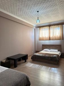 a bedroom with two beds and a table and a ceiling at Hotel Nirvana in Tbilisi City