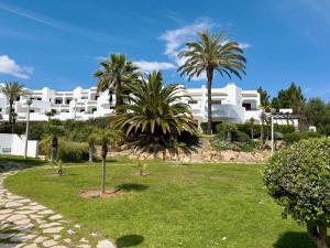 a large white building with palm trees in a park at Sunset Haven Algarve in Albufeira