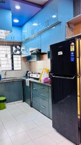 a kitchen with blue cabinets and a black refrigerator at Kaushani Homes in Nangi