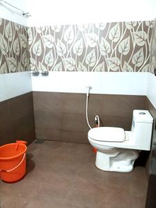 a bathroom with a white toilet and a wall at Happy Stay in Vagamon
