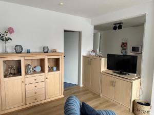 a living room with a tv and wooden cabinets at Birkenweg Ankerplatz II in Carolinensiel