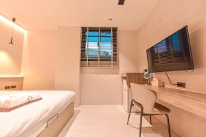 a bedroom with a bed and a desk with a television at 貳宿文旅 in Tainan +143 photos