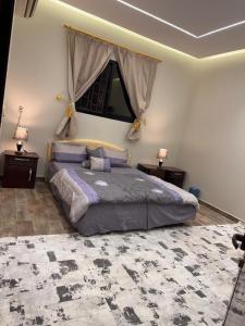 a bedroom with a large bed with two tables and a window at شالية درة الرحاب in Buraydah