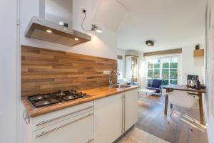 a kitchen with white cabinets and a wooden accent wall at Welcome in - Appartement met zonnig terras, nabij centrum Zoutelande I Borne 56a in Zoutelande +53 photos
