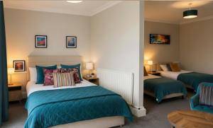a bedroom with two beds with blue and green sheets at Station Hotel in Burghead +27 photos