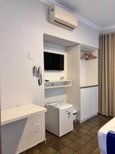 a hotel room with a bed and a television in a room at Suites Tropical in João Pessoa