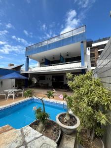 a house with a swimming pool in front of it at Suites Tropical in João Pessoa