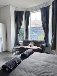 a bedroom with a bed and a couch and windows at Myrtle Villas in Hull