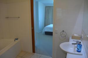 a bathroom with a sink and a shower and a bed at Wallaroo Marina Luxury Apartment in Wallaroo