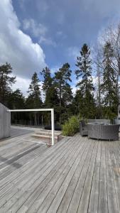 a wooden deck with a bench and chairs on it at Scandinavian Guesthouse, Archipelago Escape in Vaxholm