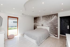 a white bedroom with a bed and a large window at Valgekodu Pesa in Papsaare