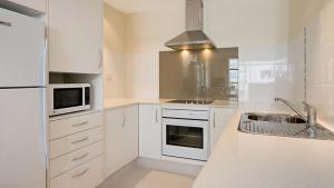 a white kitchen with a sink and a microwave at Beach House Seaside Resort in Gold Coast