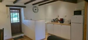 a kitchen with a refrigerator and a clock on the wall at Le Quereau in Saint-Macoux