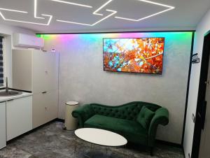 a living room with a green couch and a painting on the wall at Mini Studio Aristocrat in Târgovişte