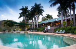 a swimming pool in front of a building with palm trees at Cedar Lake Country Resort in Nerang