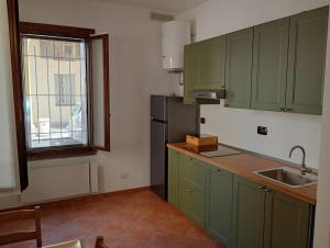 a kitchen with green cabinets and a sink and a window at La finestra sulla campana in Brescello