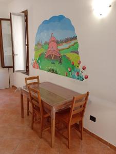 a dining room table with two chairs and a painting on the wall at La finestra sulla campana in Brescello
