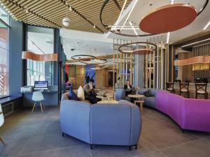 a lobby with purple couches and people sitting at tables at Ibis Aktobe in Aktobe