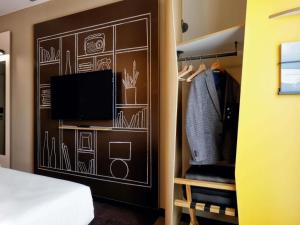 a bedroom with a wall with a tv and a closet at Ibis Aktobe in Aktobe