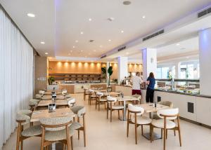 a restaurant with wooden tables and chairs and a counter at Anonymous Beach Hotel (Adults 16+) in Ayia Napa