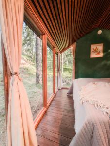 a bedroom with a bed and a large window at Minimökki Karjalohjalla in Lohja