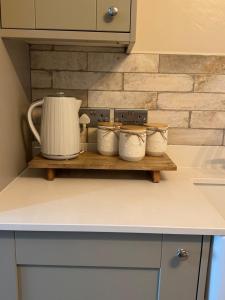 a kitchen counter with a shelf with three tea pots at Harehills House in Killingbeck
