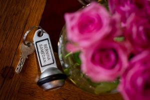 a glass vase with pink roses and a key at TH Samedan - Hotel Bernina 1865 in Samedan