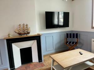a living room with a fireplace with a tv on the wall at l'Ocean in Dieppe