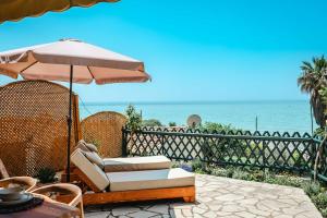 a patio with a chair and an umbrella and the ocean at Corfu Dream Apartment Chrysion in Glyfada