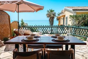 a table with chairs and an umbrella and the ocean at Corfu Dream Apartment Chrysion in Glyfada