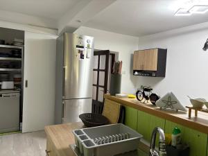 a kitchen with a stainless steel refrigerator and a table at Căsuța Verde in 2 Mai
