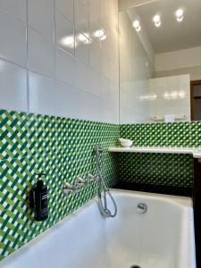 a bathroom with a tub and a green and white tiled wall at Podere Picarelly in Colonnella +74 photos