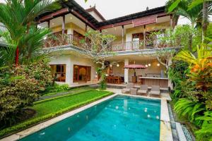 a villa with a swimming pool in front of a house at Villa Tenang in Ubud