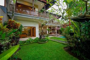a courtyard of a house with a green yard at Villa Tenang in Ubud