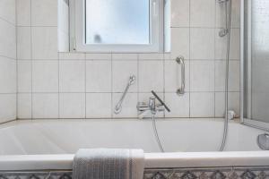a bathroom with a tub with a shower and a window at Ferienwohnung Am Seebach, 80 Qm in Titisee-Neustadt +29 photos