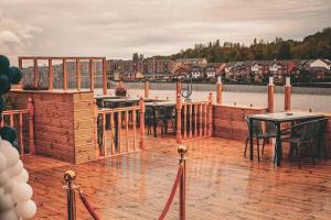 a wooden deck with tables and chairs on the water at Rivers Hotel in Newcastle upon Tyne
