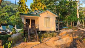 a small yellow house with a porch and stairs to it at Dumba Bay Tioman in Tioman Island